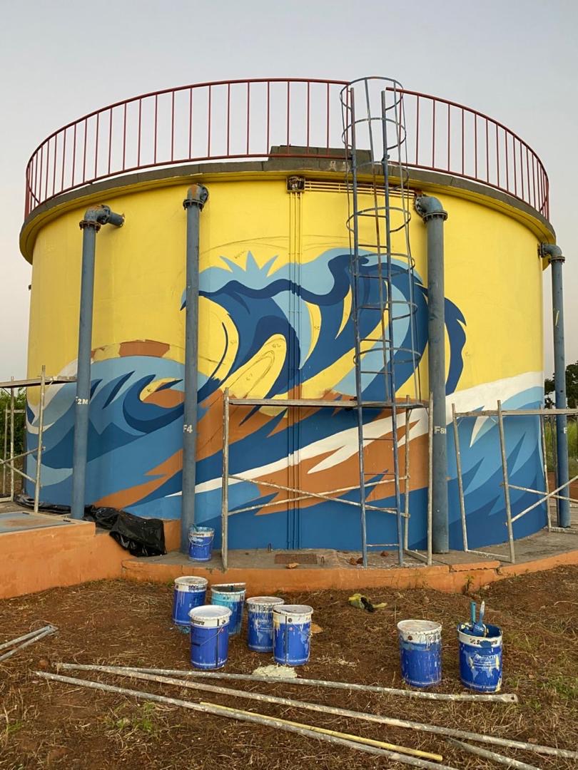 Fresque de vague bleue peinte sur le château d'eau SEN'EAU à Thiès